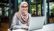 © Iwankrwn - Muslim businesswoman working on laptop in cafe. Young muslim businesswoman wearing eyeglasses and hijab sitting at table with laptop.
