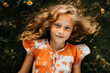 © Anna - Close-up of a smiling young girl lying in a grassy meadow with flowers.