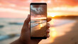 © Юлия Падина - A man's hand is holding a smartphone in close-up on the screen of which the beach and the sea are visible. The concept of technology as a part of our lives