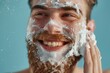Happy caucasian man takes pride in his grooming routine carefully applying shaving cream to his beard