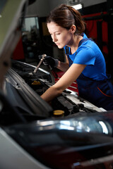 Poster - Woman auto mechanic works under an open hood