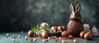 A Easter bunny made by chocolate near some chocolate eggs and spring flowers.