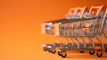 Miniature Shopping Cart On Orange Background, Concept Of Consumerism And Retail