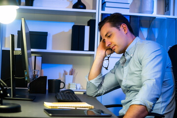 Wall Mural - Working businessman sleepy feeling with project at night time, waiting email information sending back at modern workplace. Theme of freelancer tired of remote online work in over time. Sellable.
