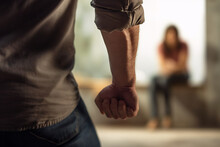 Back View Of Aggressive Man With Defocused Clenched Fist With Woman In Blurry Background