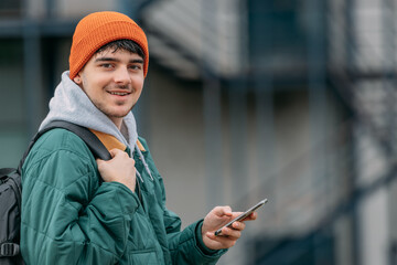 Canvas Print - young man or student with backpack on the street looking at his mobile phone