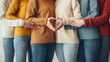 people are standing side by side, wearing colorful sweaters and jeans, forming a heart shape with their hands, symbolizing love and togetherness