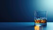 Elegant whiskey glass with ice cubes, against dark blue backdrop