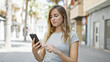© Krakenimages.com - Cool, young blonde woman in casual fashion, seriously engrossed in her smartphone outside on urban city street. concentrated young caucasian female texting, engrossed in her online lifestyle.