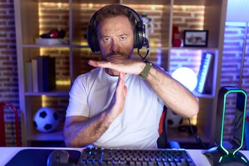 Sticker - Middle age man with beard playing video games wearing headphones doing time out gesture with hands, frustrated and serious face