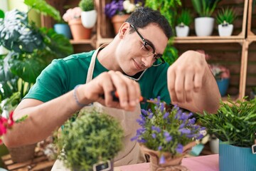 Sticker - Young hispanic man florist talking on smartphone cutting lavender plant at flower shop