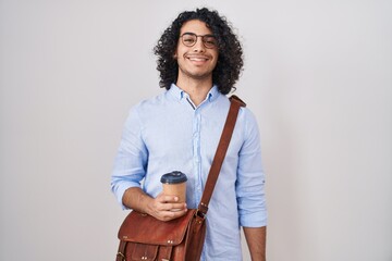 Wall Mural - Hispanic man with curly hair drinking a cup of take away coffee with a happy and cool smile on face. lucky person.