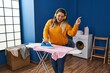 © Krakenimages.com - Young beautiful plus size woman listening to music ironing clothes at laundry room