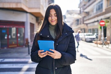 Wall Mural - Young beautiful hispanic woman smiling confident using touchpad at street