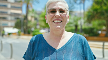 Canvas Print - Middle age grey-haired woman wearing sunglasses smiling at street