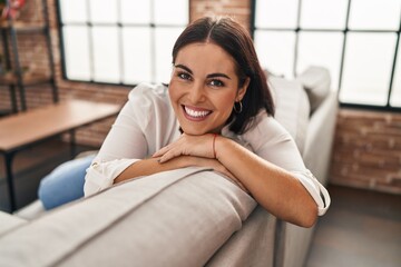 Wall Mural - Young beautiful hispanic woman smiling confident sitting on sofa at home