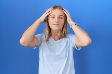 Canvas Print - Young caucasian woman wearing casual blue t shirt suffering from headache desperate and stressed because pain and migraine. hands on head.