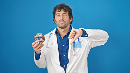 Canvas Print - Young hispanic man nutritionist holding doughnut doing thumb down gesture over isolated blue background