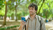 © Krakenimages.com - Young hispanic man tourist wearing backpack using smartphone at park