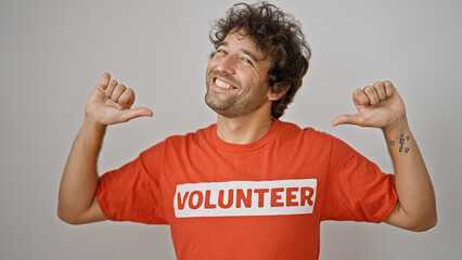 Wall Mural - Young hispanic man activist pointing to volunteer uniform smiling over isolated white background