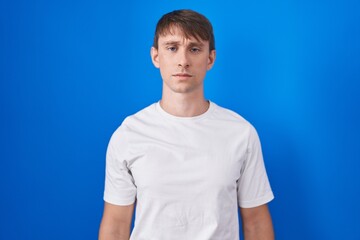 Wall Mural - Caucasian blond man standing over blue background skeptic and nervous, frowning upset because of problem. negative person.