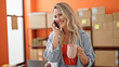 © Krakenimages.com - Young blonde woman ecommerce business worker talking on smartphone drinking coffee at office