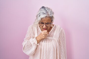 Poster - Middle age woman with grey hair standing over pink background feeling unwell and coughing as symptom for cold or bronchitis. health care concept.