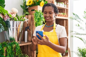 Canvas Print - Middle age african american woman florist smiling confident using smartphone at flower shop