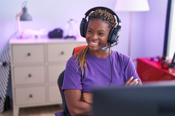 Wall Mural - African american woman streamer smiling confident sitting with arms crossed gesture at gaming room