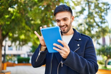 Canvas Print - Young hispanic man smiling confident using touchpad at park