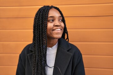 Wall Mural - African american woman smiling confident looking to the side over isolated wooden background