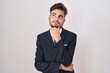 © Krakenimages.com - Young hispanic man with tattoos wearing business suit and tie with hand on chin thinking about question, pensive expression. smiling and thoughtful face. doubt concept.