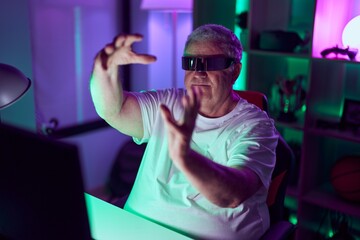 Poster - Middle age grey-haired man streamer playing video game using virtual reality glasses at gaming room