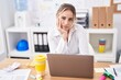 © Krakenimages.com - Young blonde woman business worker sitting on table with relaxed expression at office