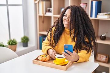 Canvas Print - African american woman having breakfast using smartphone at home