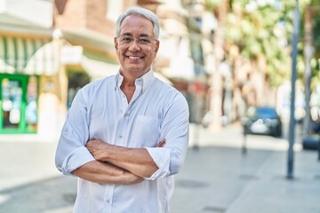 Wall Mural - Middle age grey-haired man standing with arms crossed gesture at street