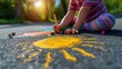 © olegganko - A child draws the sun with crayons on the asphalt. Spring sunny day