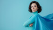 © JW Studio - Brave woman keeps arms on hips, smiling confident, casting a superhero with blue cape .Ambition and business success concept. Leadership hero power, motivation and inner strength symbol, copy space