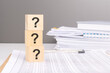 question marks on wooden blocks. business concept. gray background, financial document.