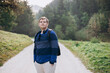 Young male with backpack hiking on the road in nature. 30s men walking on nature in sport clothes. Guy portrait lifestyle.