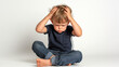 © Natali - a baby boy headache and migraine sitting with back against white wall on the floor,copy space
