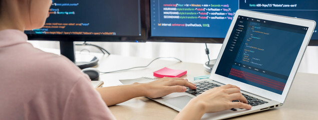 Cropped image of female web developer coding on laptop while computer displayed program and software code at modern office. Close up businesswoman hand focus on analysis data. Burgeoning.