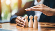 © Your Hand Please - Woman's hands shield wooden figures, embodying protection and security with a determined gesture, symbolizing strength and guardianship