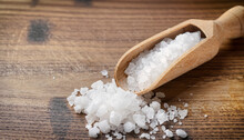 Salt Crystals With Wooden Scoop On Wooden Table