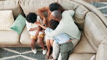 Happy, tickling and parents with children on sofa having fun, bonding and relaxing together at home. Laughing, love and top view of boy kids playing with mother and father in living room at house.