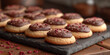 Freshly baked cookies dipped in rich chocolate and garnished with raspberries sprinkles, presented on a slate board.
