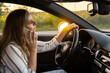 © anna.stasiia - Young woman using mobile phone while driving car on highway road during sunset. Womandriver has accident calling with smartphone for help. Business woman busy driving