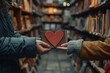 Close-up of hands exchanging heart-shaped bookmarks in a quaint bookstore