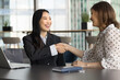 © fizkes - Two happy diverse office colleague women shaking hands, laughing, meeting for successful teamwork, partnership, getting agreement. Satisfied client giving greeting handshake to Asian manager
