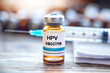 HPV vaccine vial with syringe and medical background, focus on label, for health campaigns on human papillomavirus prevention and cancer awareness